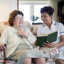 Older woman and caregiver reading together